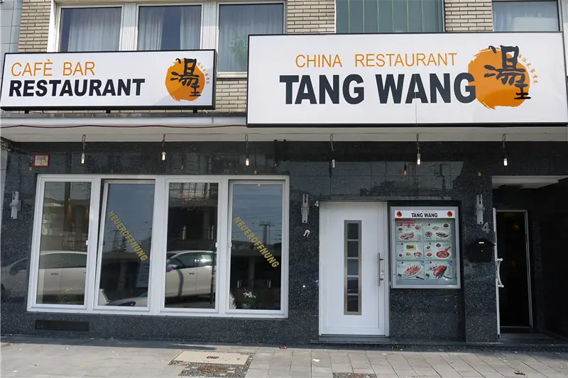 Die Fassade in der Maximinenstraße: Leuchtschild „China Restaurant Tang Wang“ mit dem orangen Logo über dem Eingang